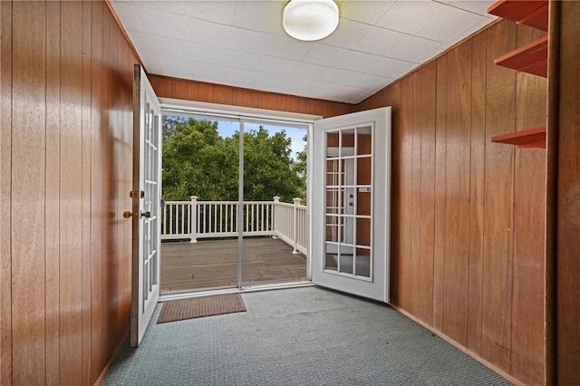 doorway with light carpet, wooden walls, and french doors