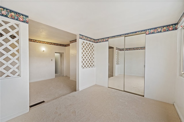 unfurnished bedroom with a closet and light carpet