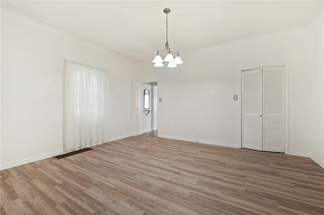 spare room with a notable chandelier, crown molding, and wood-type flooring