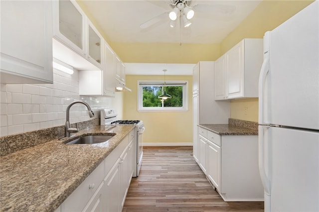 kitchen featuring white cabinets, light hardwood / wood-style flooring, stone counters, and white appliances