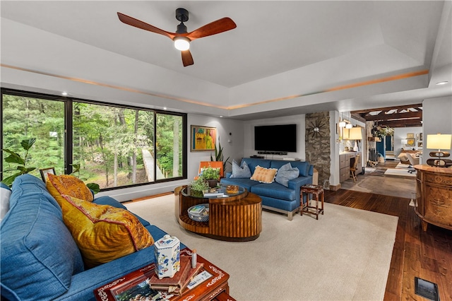 living room with ceiling fan, a raised ceiling, and hardwood / wood-style floors