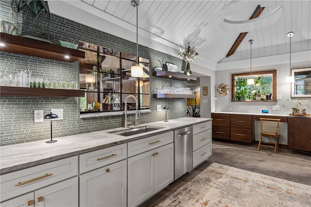 kitchen featuring light stone counters, white cabinets, sink, hanging light fixtures, and backsplash