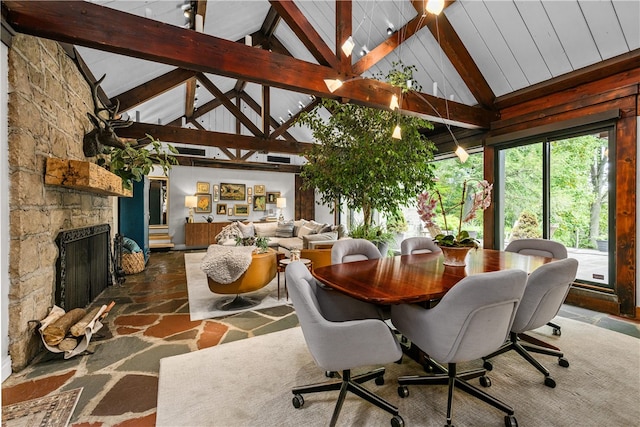 dining area with beamed ceiling, a fireplace, and high vaulted ceiling