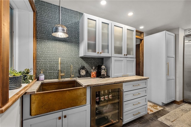 kitchen featuring tasteful backsplash, dark hardwood / wood-style flooring, wine cooler, light stone countertops, and hanging light fixtures