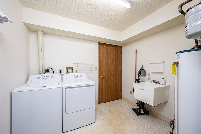 laundry room featuring sink, a textured ceiling, washer and clothes dryer, and water heater