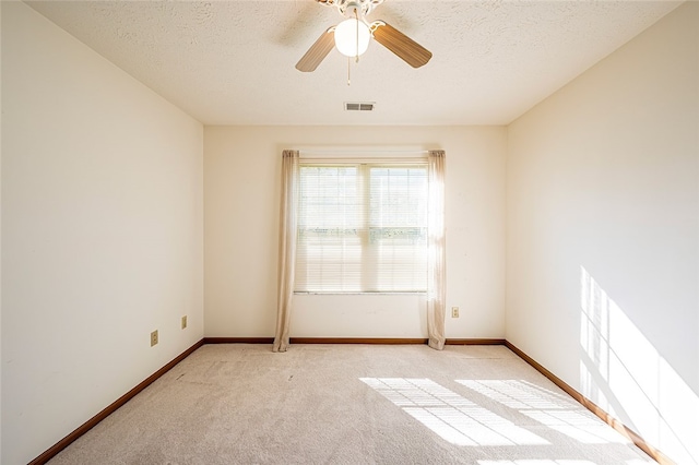 empty room with ceiling fan, light colored carpet, and a textured ceiling