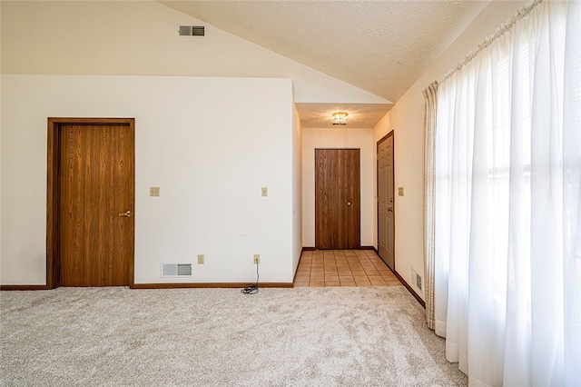 unfurnished room with light colored carpet, lofted ceiling, and a textured ceiling