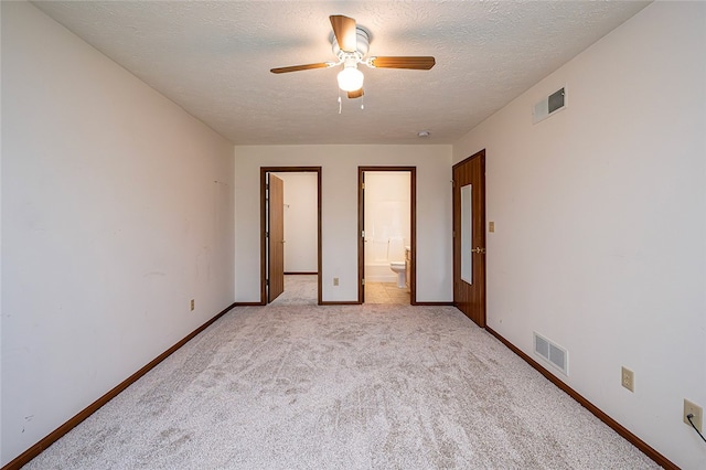 unfurnished bedroom featuring a textured ceiling, connected bathroom, light colored carpet, and ceiling fan