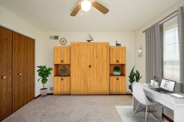 carpeted office featuring a textured ceiling and ceiling fan