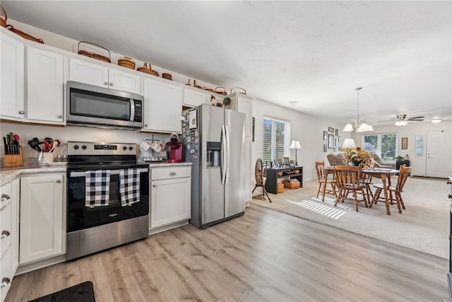 kitchen with light wood-type flooring, decorative light fixtures, white cabinetry, appliances with stainless steel finishes, and ceiling fan with notable chandelier