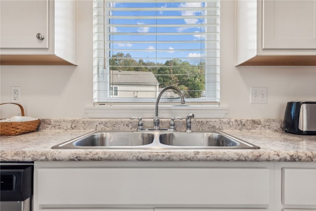 kitchen featuring stainless steel dishwasher, sink, and white cabinets