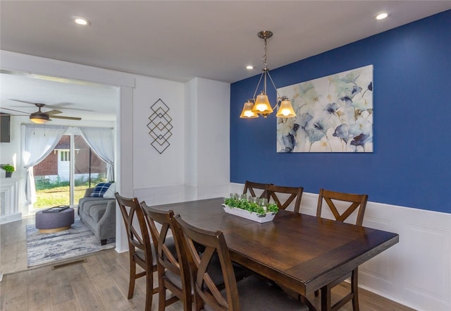 dining room with wood-type flooring and ceiling fan with notable chandelier