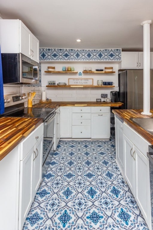 kitchen with white cabinets, appliances with stainless steel finishes, decorative columns, and butcher block counters