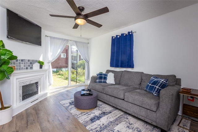 living room featuring hardwood / wood-style flooring, a high end fireplace, ceiling fan, and a textured ceiling