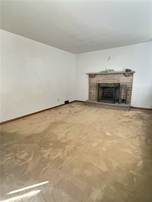 unfurnished living room with carpet floors and a stone fireplace