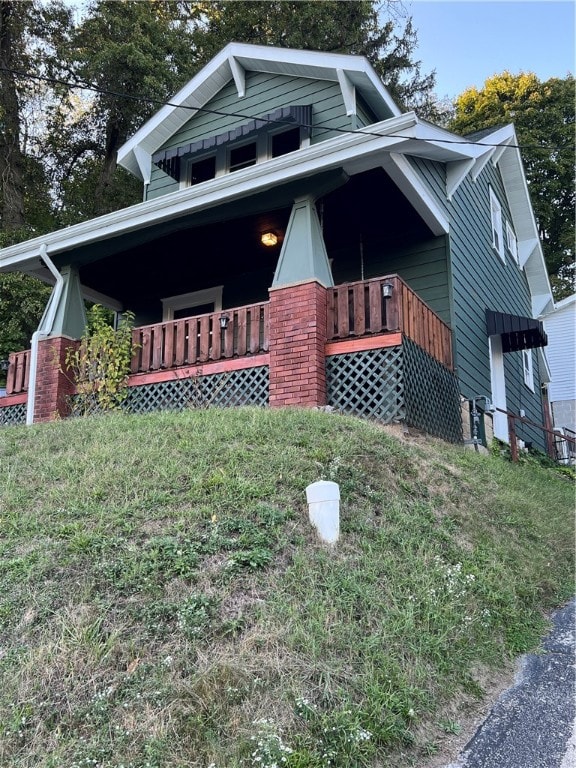 view of side of property with a porch and a lawn