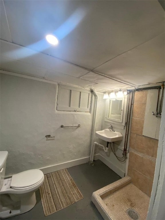 bathroom with sink, toilet, a shower, and concrete floors