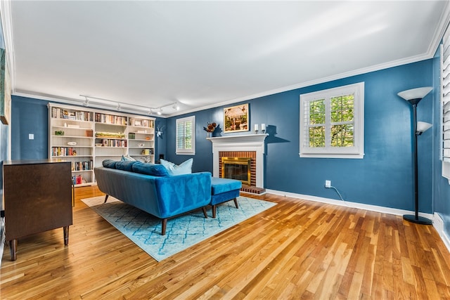 living room with ornamental molding, track lighting, a fireplace, and hardwood / wood-style floors