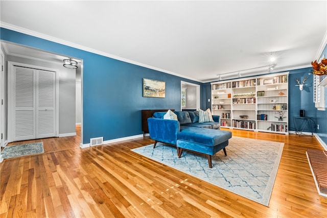 living area with wood-type flooring, ornamental molding, and rail lighting