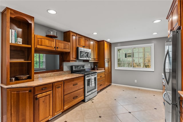 kitchen with stainless steel appliances, light stone counters, and light tile patterned floors