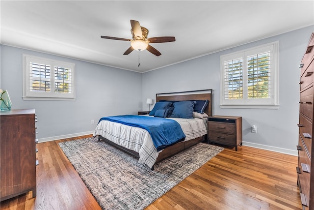 bedroom with crown molding, hardwood / wood-style floors, multiple windows, and ceiling fan