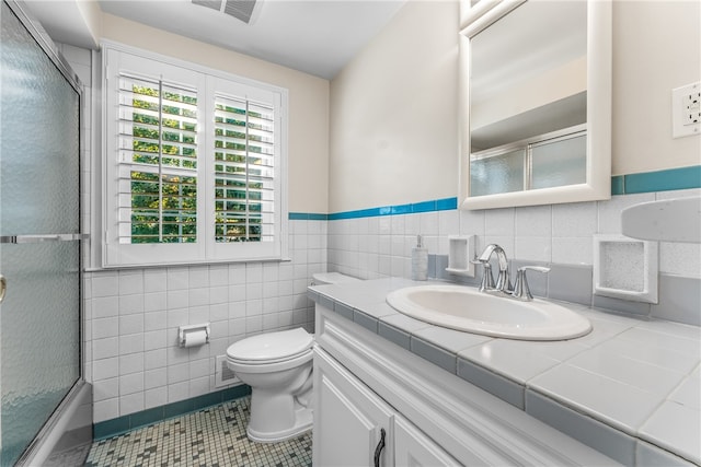 full bathroom with enclosed tub / shower combo, toilet, tile patterned floors, tile walls, and vanity