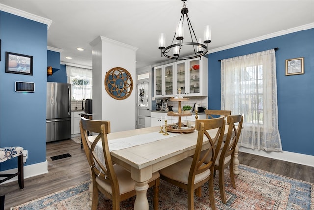 dining area with ornamental molding, a chandelier, and dark hardwood / wood-style floors