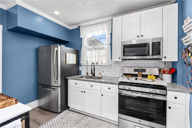 kitchen featuring ornamental molding, white cabinets, appliances with stainless steel finishes, and sink