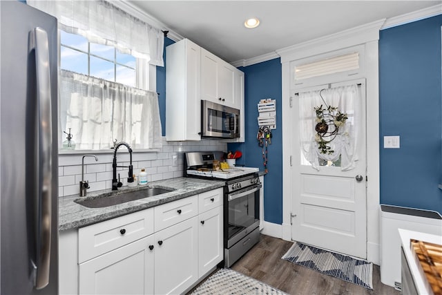 kitchen with crown molding, sink, light stone counters, stainless steel appliances, and white cabinetry