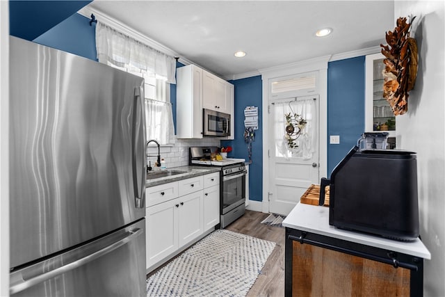 kitchen featuring crown molding, decorative backsplash, white cabinetry, and stainless steel appliances