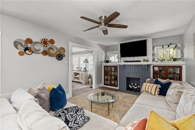 living room featuring a brick fireplace, light hardwood / wood-style floors, and ceiling fan