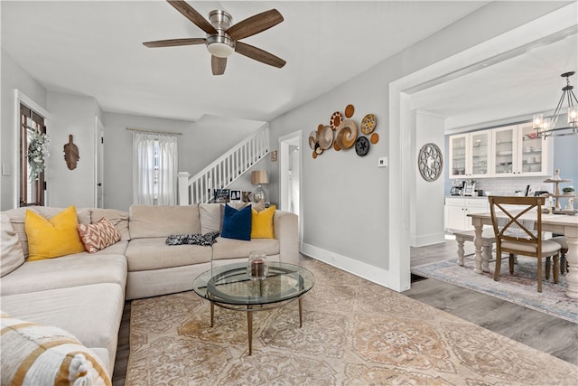 living room featuring ceiling fan with notable chandelier and wood-type flooring