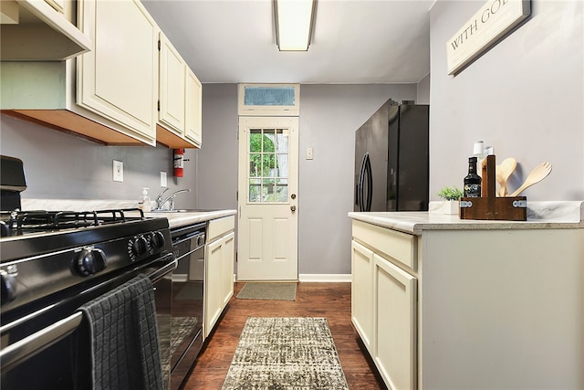 kitchen featuring cream cabinets, black appliances, sink, and dark hardwood / wood-style flooring