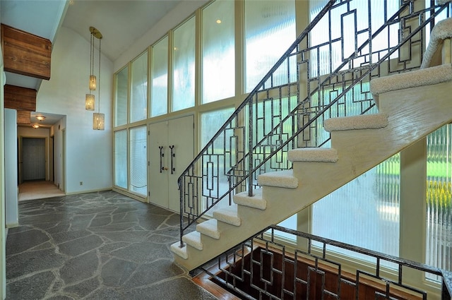 staircase featuring a towering ceiling and carpet