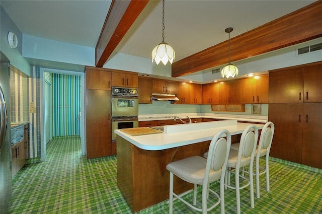 kitchen with double oven, pendant lighting, beamed ceiling, and a center island