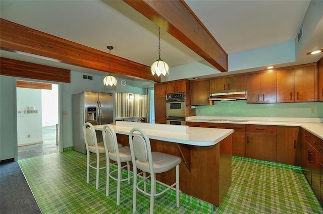 kitchen featuring stainless steel fridge, double oven, beam ceiling, under cabinet range hood, and light countertops
