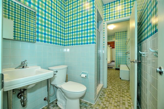 bathroom with tile patterned flooring, toilet, sink, tile walls, and a shower with shower door