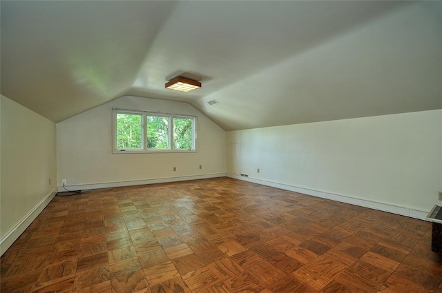 additional living space with dark parquet flooring and vaulted ceiling