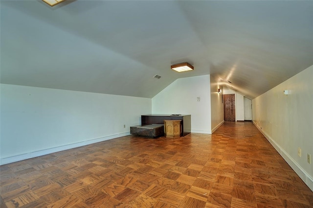 bonus room with lofted ceiling and dark parquet floors