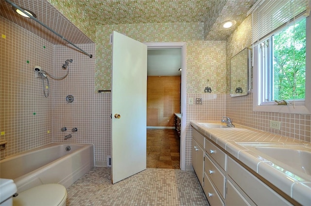 full bathroom with vanity, tiled shower / bath, tile walls, tile patterned floors, and toilet