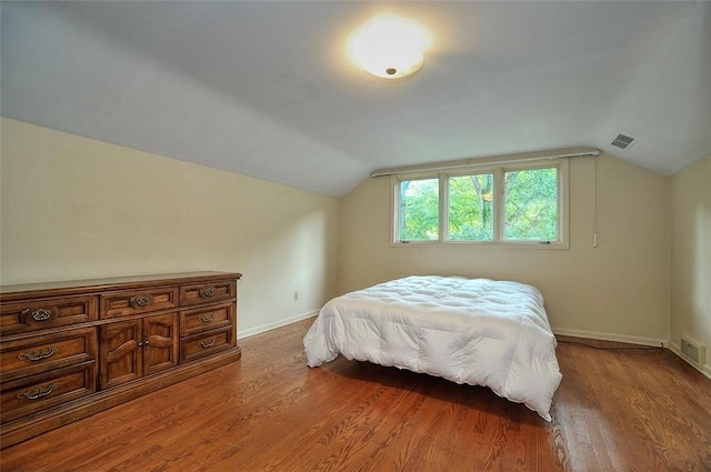 bedroom with light wood-style flooring, lofted ceiling, and baseboards