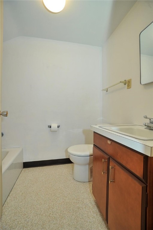 bathroom with vanity, a tub to relax in, and toilet