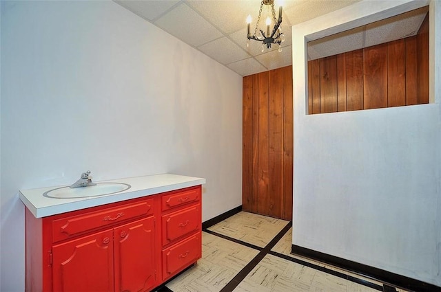 bathroom featuring a chandelier, wood walls, a paneled ceiling, tile patterned floors, and baseboards