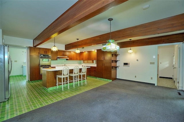 kitchen with carpet, freestanding refrigerator, light countertops, multiple ovens, and beamed ceiling