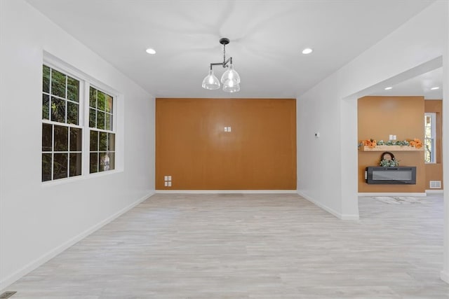 spare room with an inviting chandelier and light hardwood / wood-style floors