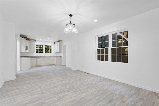 unfurnished living room featuring a chandelier and light hardwood / wood-style flooring