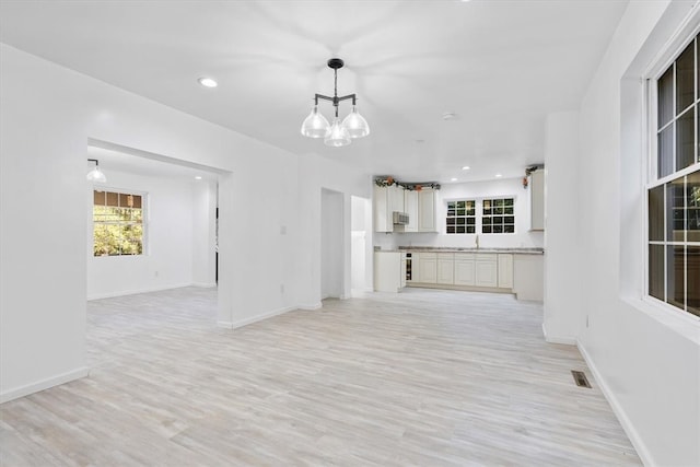 unfurnished living room with light hardwood / wood-style flooring and a chandelier