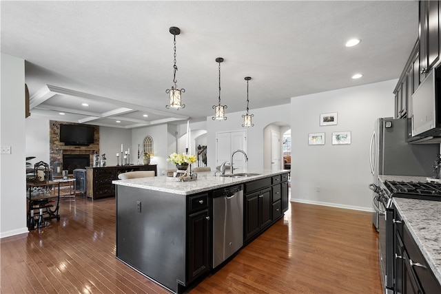 kitchen featuring stainless steel appliances, dark wood-type flooring, a kitchen island with sink, and sink