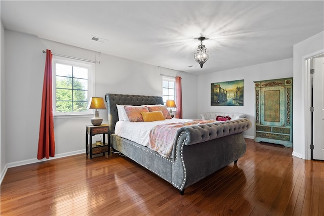 bedroom featuring an inviting chandelier, hardwood / wood-style floors, and multiple windows