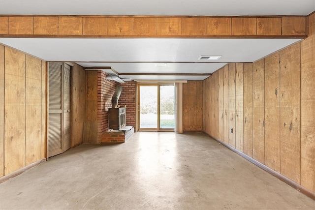 unfurnished living room featuring wooden walls and a wood stove